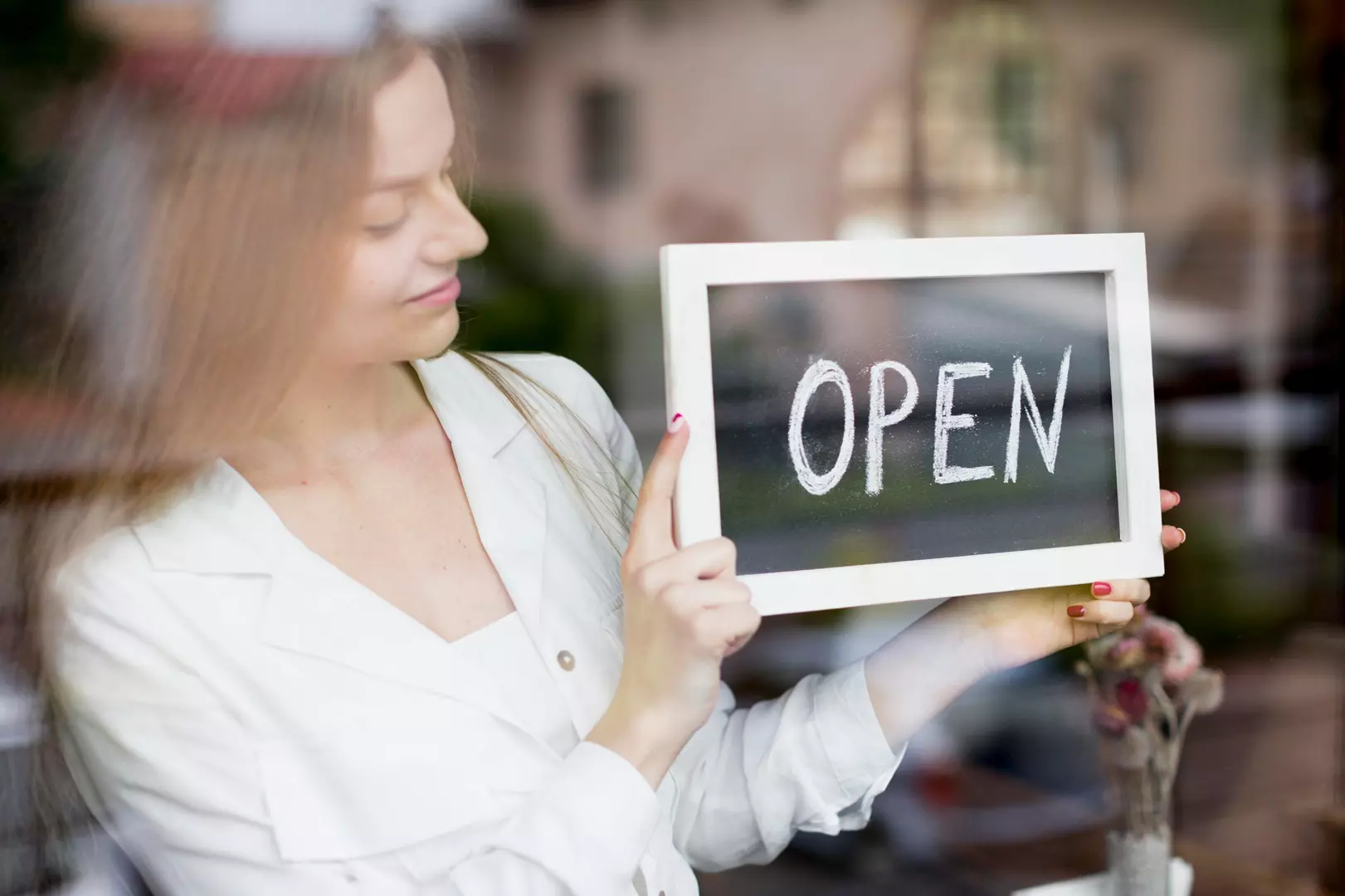 woman-holding-open-sign-coffee-shop-window